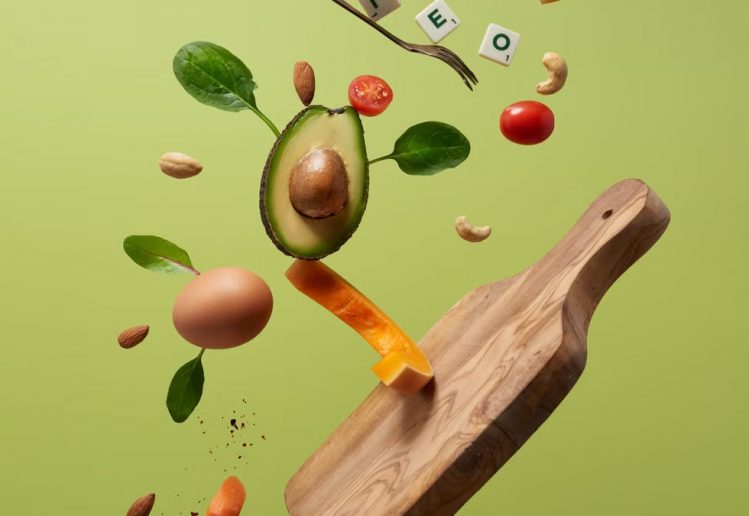 A creative arrangement of paleo diet ingredients floating above a wooden board on a green background.
